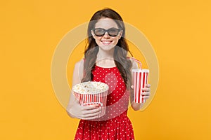 Smiling young brunette woman girl in red summer dress, 3d glasses isolated on yellow background. People lifestyle