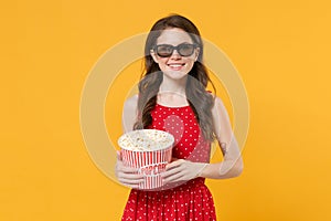 Smiling young brunette woman girl in red summer dress, 3d glasses posing isolated on yellow wall background. People