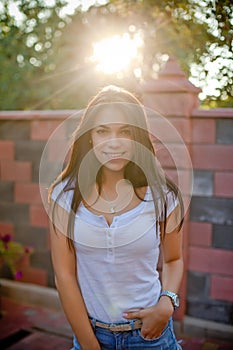 Smiling young brunette woman posing in yard of her residence
