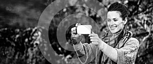 Woman taking photo with mobile while relaxing in autumn park