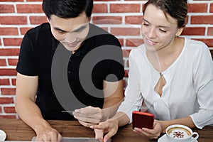 Smiling young business couple loves Asian man and caucasian woman holding credit card for online shopping and paying in social