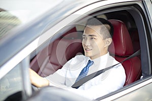 Smiling asian young business man driving a car