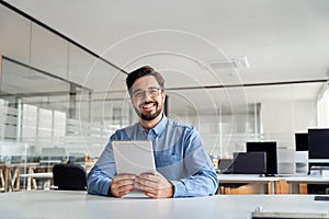 Smiling young business man manager with tab sitting in office. Portrait.