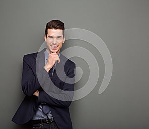 Smiling young business man standing with hand to chin