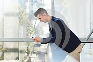 Smiling young business man standing with smart phone