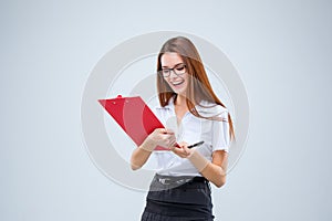 The smiling young business woman with pen and tablet for notes on gray background