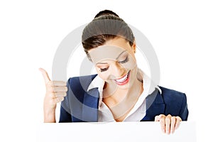 Smiling young business woman showing blank signboard