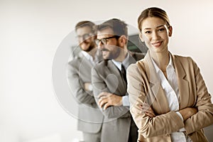 Smiling young business woman standing with group of corporate colleagues in a row together