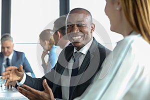 Smiling young businessman discussing with female colleague in board room