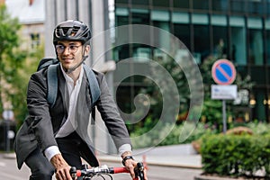 Smiling young businessman in helet riding a bike