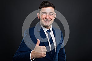 Smiling young businessman holding thumb up