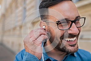 Smiling young businessman listening music on headphones