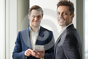 Smiling young businessman looking at camera, application develop