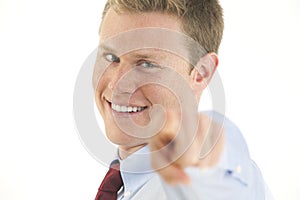 Smiling young businessman pointing finger at camer