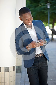 Smiling young businessman sending text message by cellphone