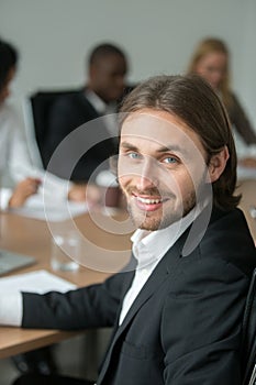Smiling young businessman in suit looking at camera at meeting