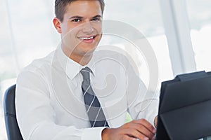 Smiling young businessman working on his tablet pc