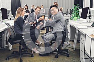 Smiling young businesspeople drinking coffee and talking