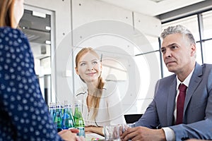 Smiling young businesswoman with colleagues in board room