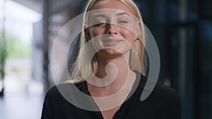 Smiling young businesswoman with tablet standing in office indoors looking at camera. Portrait of gorgeous confident