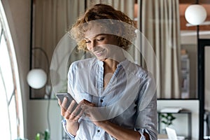 Smiling young businesswoman use cellphone texting online