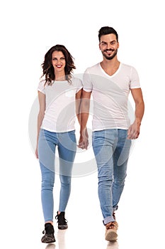 Smiling young casual couple is walking forward