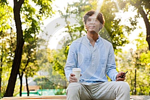 Smiling young casual man holding mobile phone