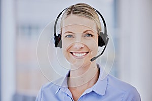 Smiling young caucasian female call centre agent talking on headset while working in an office. Confident and happy