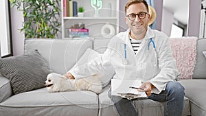 Smiling young caucasian man doubling as home vet, sitting on sofa, holding clipboard, administering pet care to adorable dog