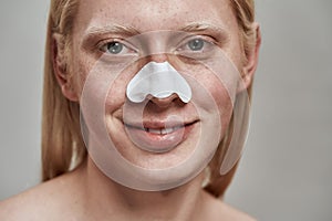 Smiling young caucasian man using nose pore strips