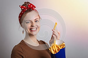 Smiling young Caucasian woman girl holding eating big size french fries portion