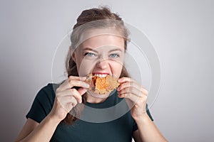 Smiling young Caucasian woman girl holding eating fried chicken  drumstick