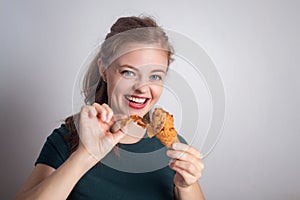 Smiling young Caucasian woman girl holding eating fried chicken  drumstick