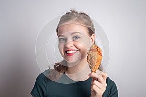 Smiling young Caucasian woman girl holding eating fried chicken  drumstick