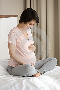 Smiling pregnant woman touch caress baby bump photo