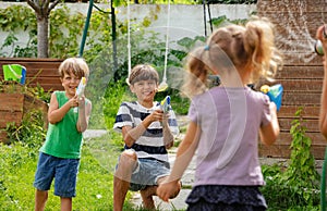 Smiling young children partake in water pistol play at backyard