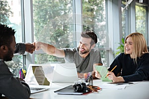 Smiling young colleagues sitting in office coworking