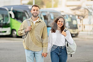 Smiling young couple with backpacks posing at the airport entrance