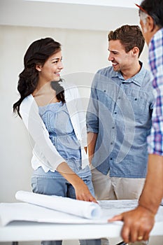 Smiling young couple discussing house plan with architect. Young couple smiling while discussing house plans with