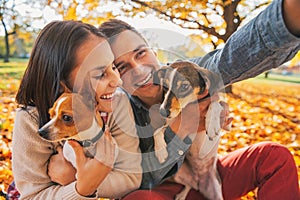 Smiling young couple with dogs outdoors making selfie