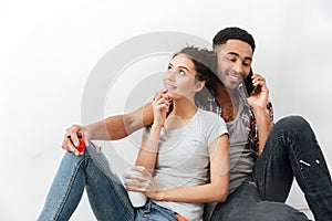 Smiling young couple drinking coffee and talking on cell phone