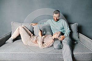 Smiling young couple embracing while looking at smartphone spending their time together at home