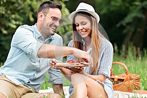 Smiling young couple enjoying their time in a park, having a casual romantic picnic
