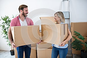 Smiling young couple holding boxes and packing for moving