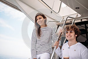 Smiling young couple holding glasses with beverage while travelling on yacht