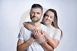 Smiling young couple hugging, studio portrait over light background