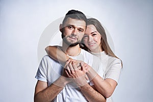 Smiling young couple hugging, studio portrait over light background