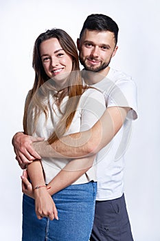 Smiling young couple hugging, studio portrait over light background