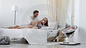Smiling young couple looking at a blurred little baby sleep in bed at home