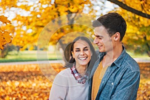 Smiling young couple outdoors in park in autumn